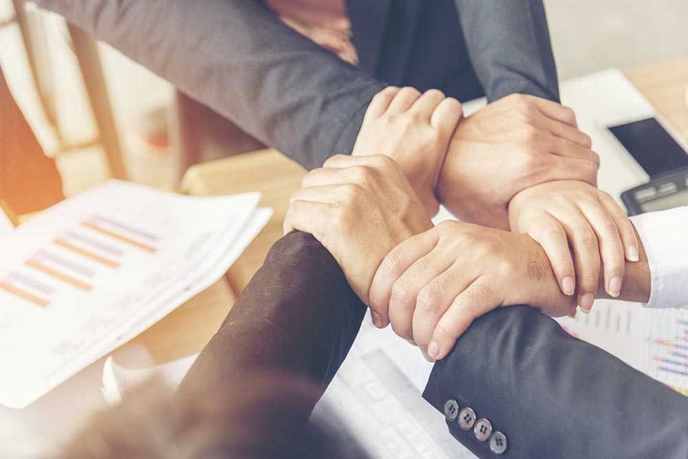 Four Buyers agents linking arms by holding each others wrist to form a square